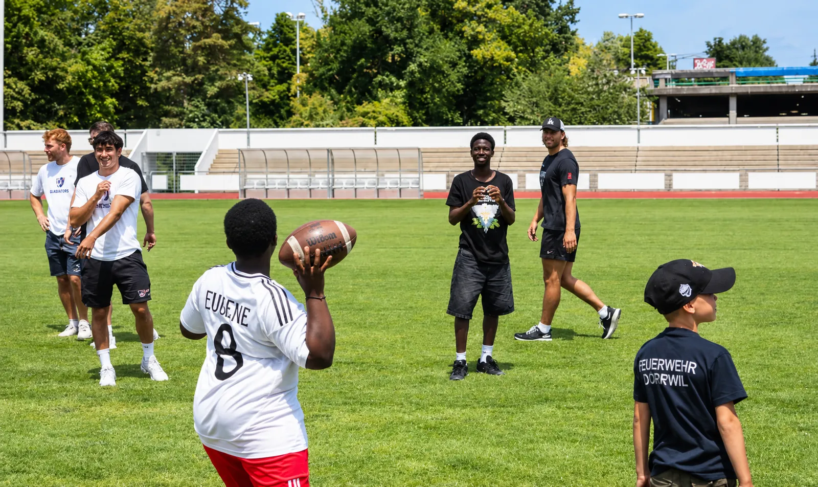 Kinder und Spieler werfen einen Football auf dem Feld